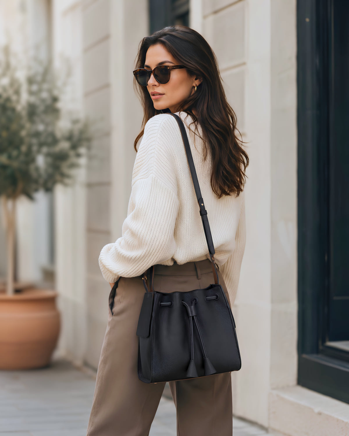The Cove in onyx leather, carried on the shoulder with the drawstring gathered at the mouth