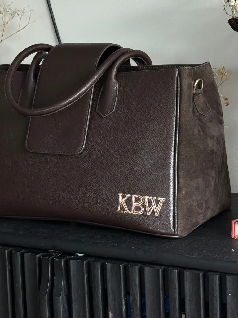 Pale and pink outlined KBW initials on a dark leather bespoke tote.