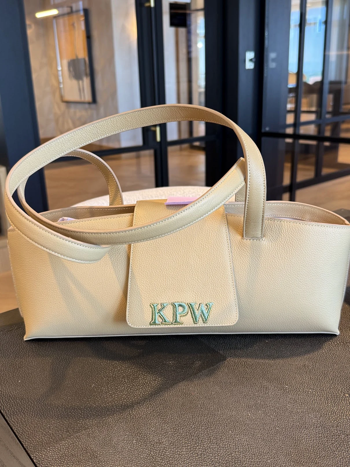 Green KPW initials with pale outlines and a painted dimensional edge on a cream leather flap.