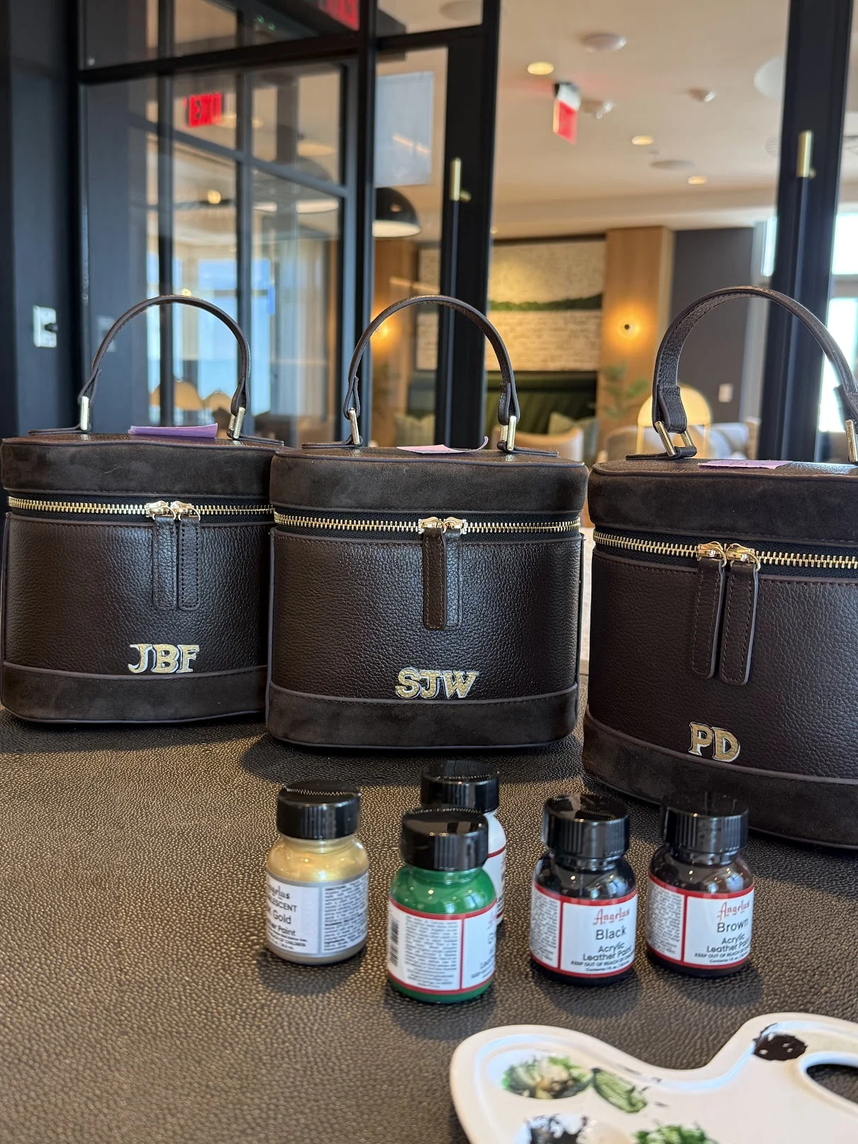 Three brown Lockets with JBF, SJW and PD initials, alongside paint bottles and a palette.